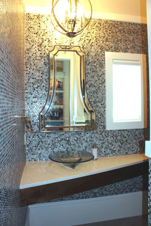 This is the coolest auxiliary bathroom I have ever had the pleasure to design!  This bath is accessible near the kitchen and garage.  The slanted countertop provides more open space, looks light and airy, and gives more counter space.  The walls are blue glass Lunada Bay penny round mosaic tiles.