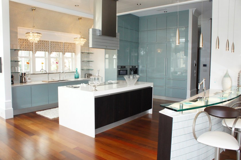 Here you can see how beautifully the Ipe wood floors contrast with the coolness of the Poggen Pohl blue glossy cabinets.  Notice the island, with its white countertop waterfalling down the sides for a modern and lightening effect.  