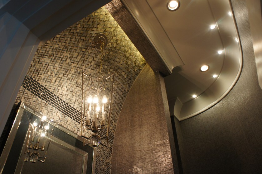 The top of this vanity wall curves out and ends in a recessed cove that lights up the wall tile and shows off the architecture.