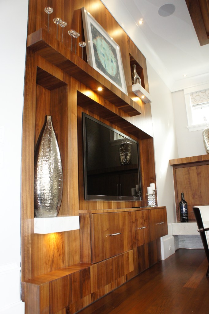 I designed this media wall to be asymmetrical, with mantle, shelves and t.v. console at varying depths.  It is made from quarter sawn maple in a walnut finish.  Instead of trying to make the t.v. the focal point, we succeeded in making that whole area a large sculptural feature.