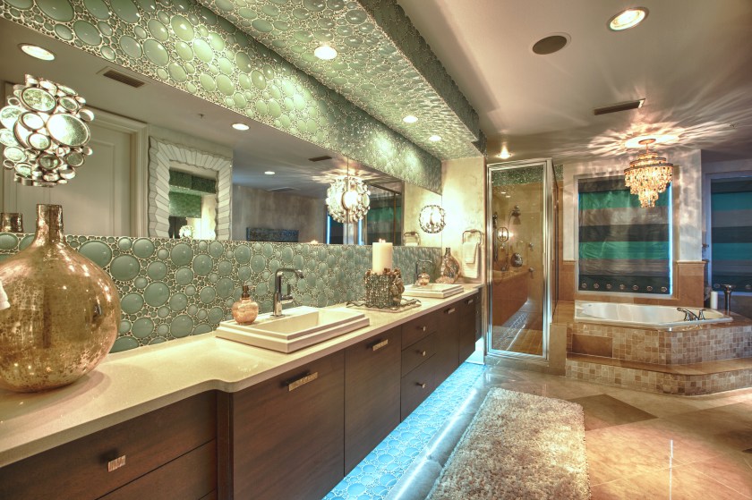 Rather than match the existing travertine underneath the cabinets, where the old cabinets were removed, we ran the green glass tiles down below.  This helped reinforce the floating effect we were going for!  The three bubble glass sconces were ideal, and looked as if they were meant for exactly this bathroom! 