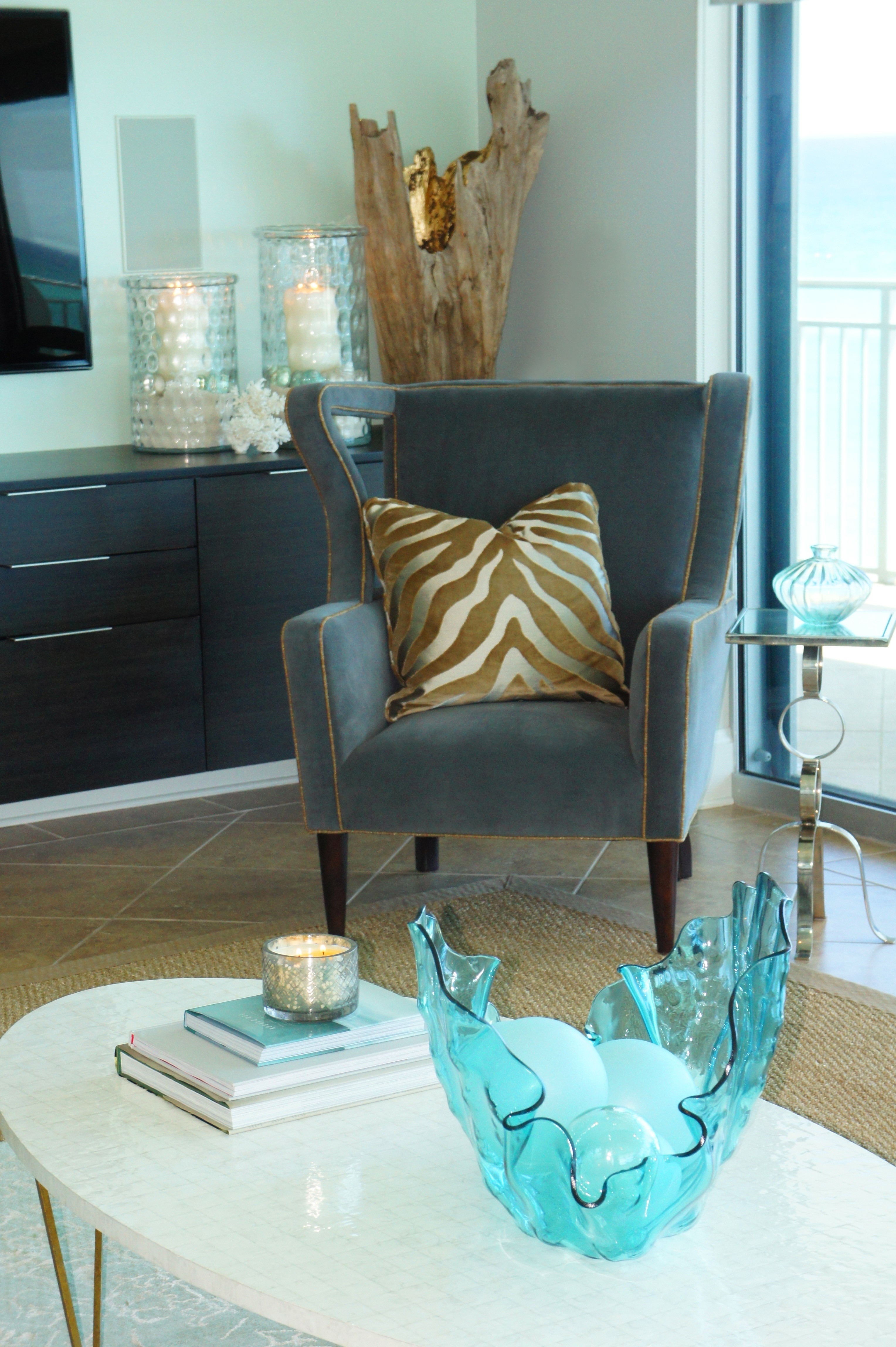 This corner is cozy with its Century Furniture contemporary wing chair, covered in a charcoal velvet and shimmering gold linen welt.  The gold velvet zebra pillow and glowing gold of the driftwood sculpture, along with the candle light radiate nicely out from all the gray and green.