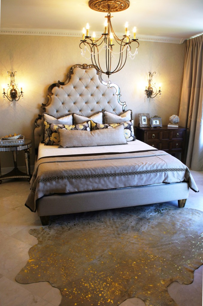 Guest Room After: Again, I got rid of the gold walls, and replaced them with a cream paint, and embroidered cream wallcovering on the bed wall.  The tall upholstered bed by Hooker Furniture provided adequate drama and "curve" appeal. I installed some new sconces, replaced the chandelier, and added some tone-on-tone draperies in cream.  The gold-splattered cowhide at the foot of the bed adds some warmth to the room.