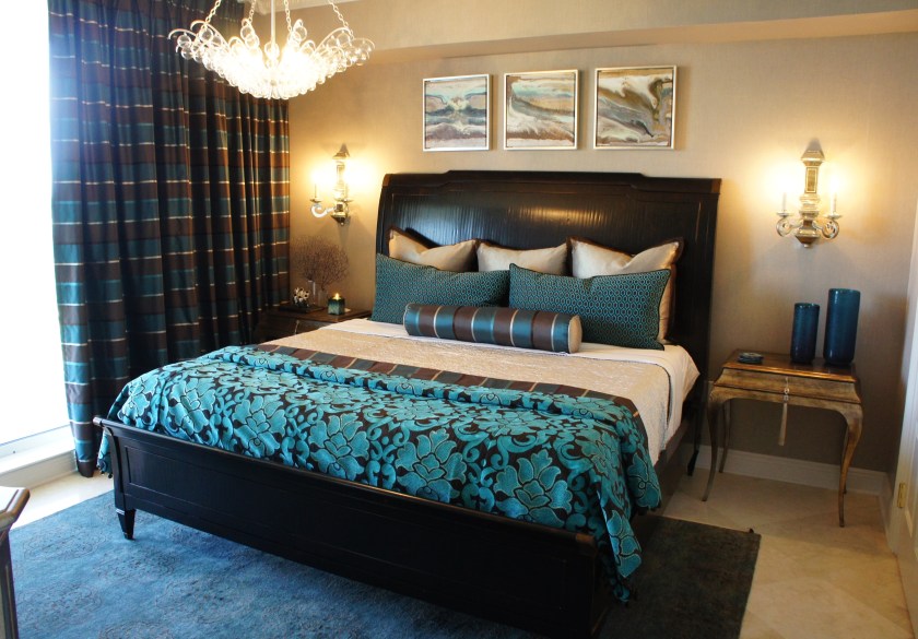 I decided to choose a design that is slightly more masculine for this room.  With taupe as the backdrop, I added in layers of gray, peacock blue and brown. The new mirrored sconces highlight the silver flecks in the fabric wall covering.  