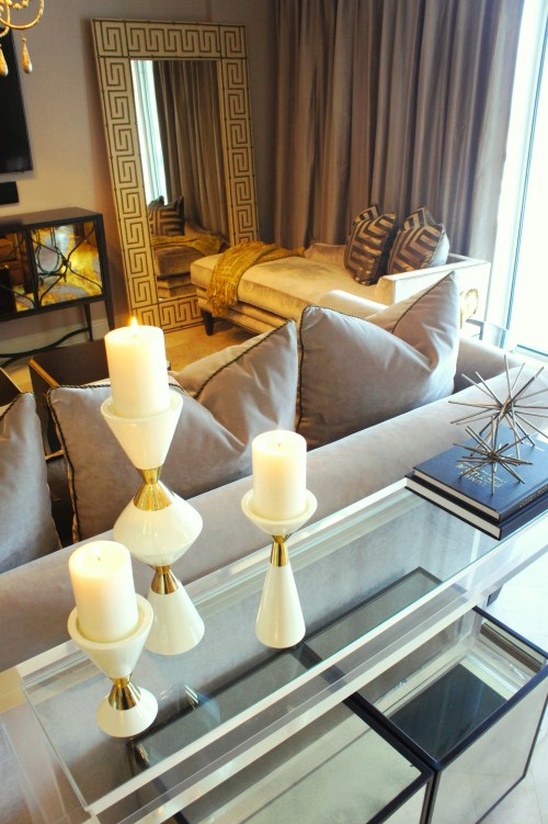 The corner of the room was best furnished with a luxurious Century chaise lounge, covered in velvet! The fretwork pillows tie in the greek key pattern in the mirrors.  To help balance the gold of the wool Oushak rug and accents, I covered the sofa in a plush, matte gray velvet. Behind the sofa, I chose to use a glass and acrylic sofa table that added a modern touch, while remaining simple enough to not take away from the lines of the sofa.  