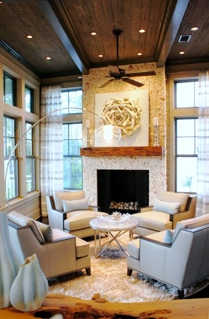 The long layout of this room called for a second seating area--one that enjoys the fireplace, and promotes conversation. The modern gray leather club chairs are centered around a round, Century Furniture mother of pearl table. The floor lamp has an exaggerated arch that allows the light to be centered over the arrangement, while not taking away from the view, or the lines of the room.