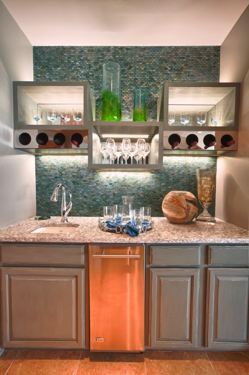 We did a partial demo of the Wet Bar to remove the generic upper cabinets.  We designed this contemporary wine glass and bottle storage system at alternating heights, then added some up-and down-lighting that accents the sleek glass tile.  