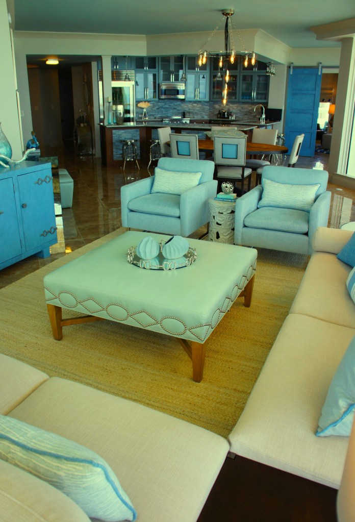 Having a large leather ottoman, versus a cocktail table allows for more versatility and softness/comfort.  You can add a tray if you need a place to set a drink!  This square ottoman is made by Lee Industries.