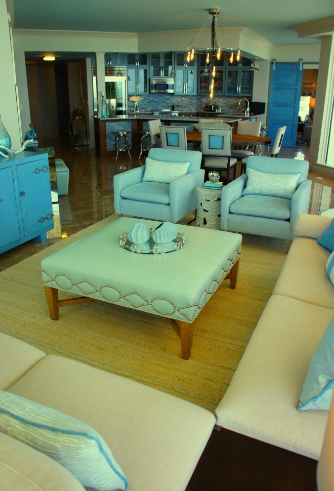 Having a large leather ottoman, versus a cocktail table allows for more versatility and softness/comfort.  You can add a tray if you need a place to set a drink!  This square ottoman is made by Lee Industries.