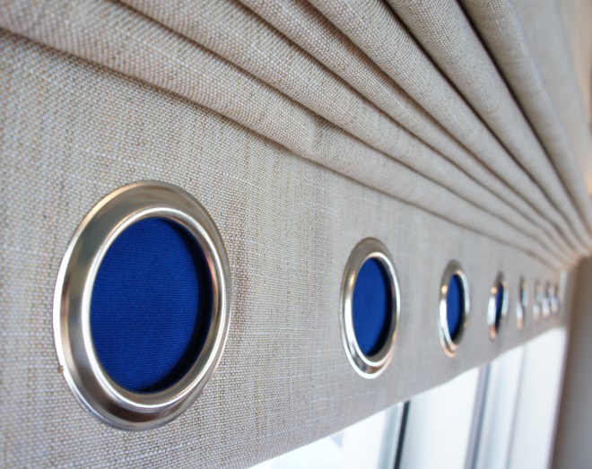 I wanted the large roman shades to remain mostly neutral, but I felt they needed some color and interest. Instead of doing a typical accent color band at the bottom, I chose to use nautical grommets on a reveal band at the bottom.  Behind the grommets, I designed a cobalt liner, which created the hint of color I wanted.