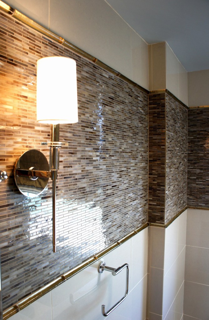 The horizontal band of tile is transitioned into the sleek porcelain tile with some taupe glass pencil trim.