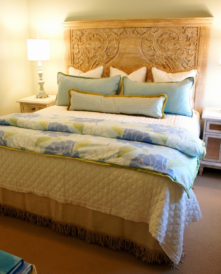 In this room, I used this fabulous carved wood headboard that I found at Nest Interiors, and paired it with some jute fringe euros, and some custom pillows. I absolutely love the aqua, green and periwinkle color combination in this foot blanket!